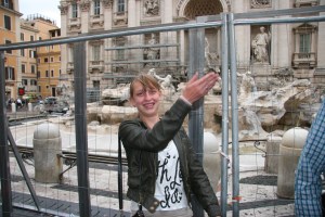 Brittney throws a coin into the dry Trevi Fountain.